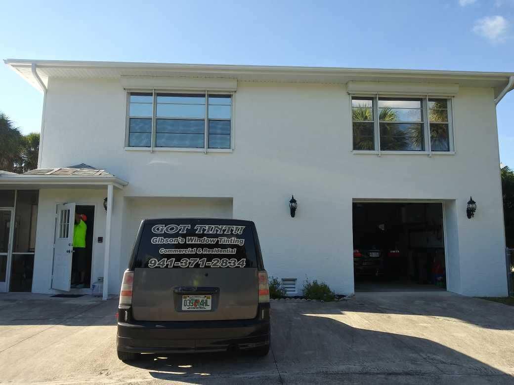 White two-story building with a black van parked in front and an open garage bay on the right.