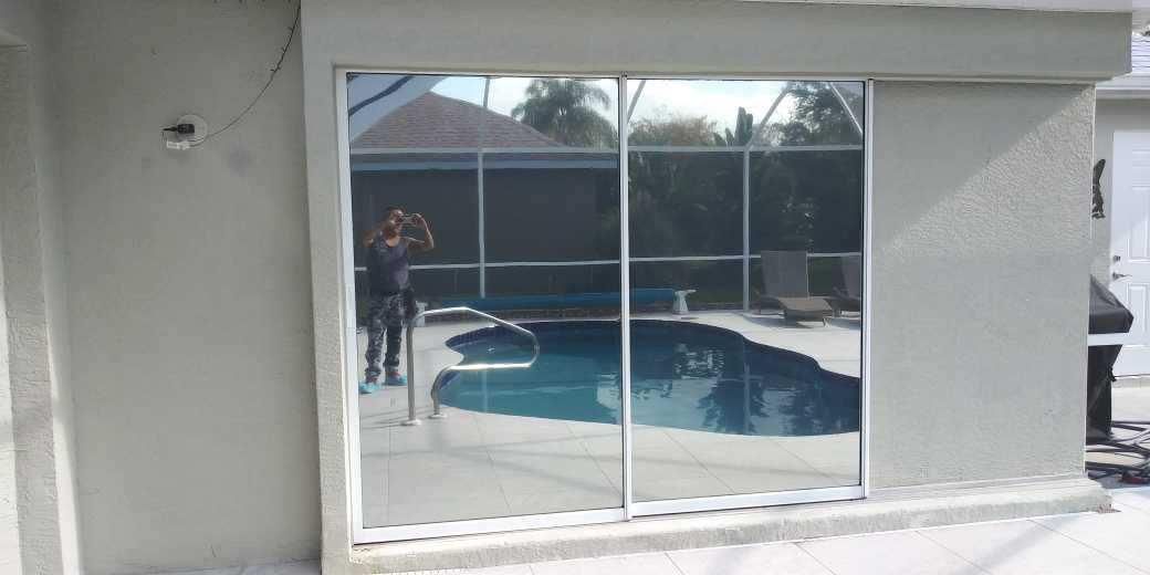 Sliding glass doors opening to a screened pool area with blue water and a patio.