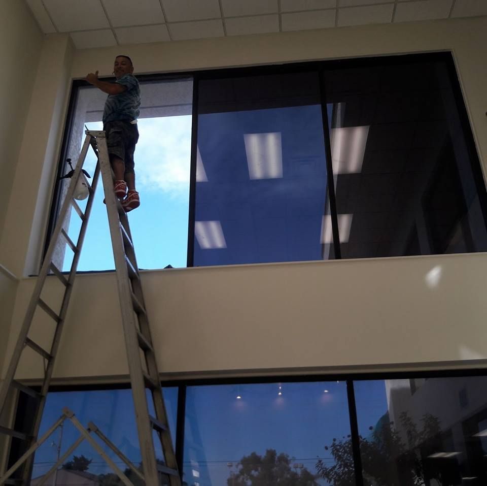 Person on a ladder cleaning a high window inside a building