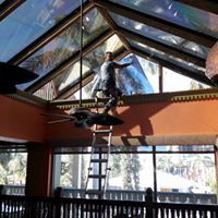 Worker on a ladder painting a glass-roofed indoor space