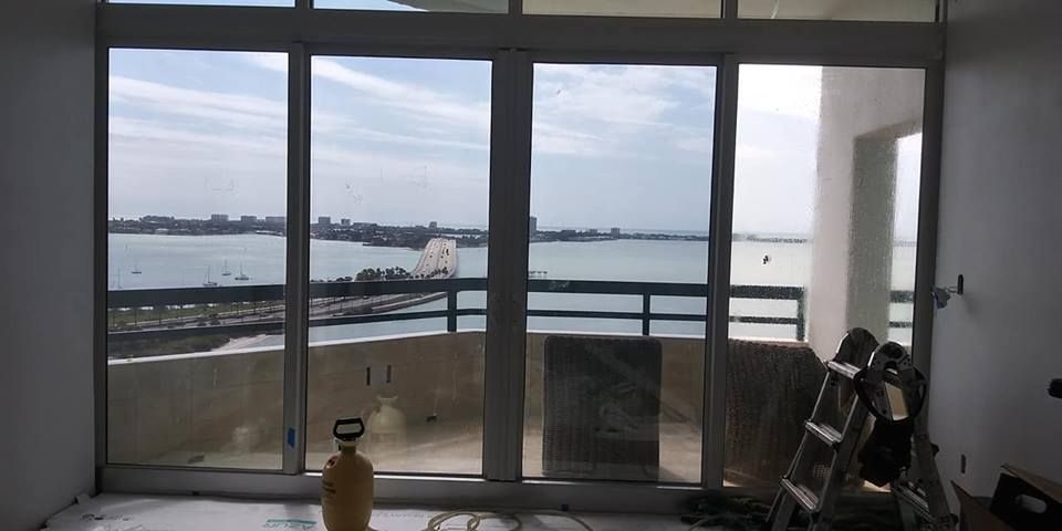 Balcony view through sliding glass doors with water, city skyline, and a reclining chair inside