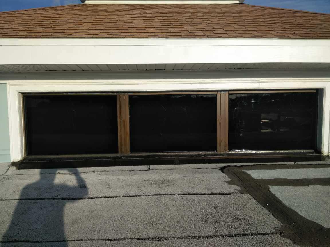 Two-car garage with closed dark doors beneath a white trim and wood-sided exterior.
