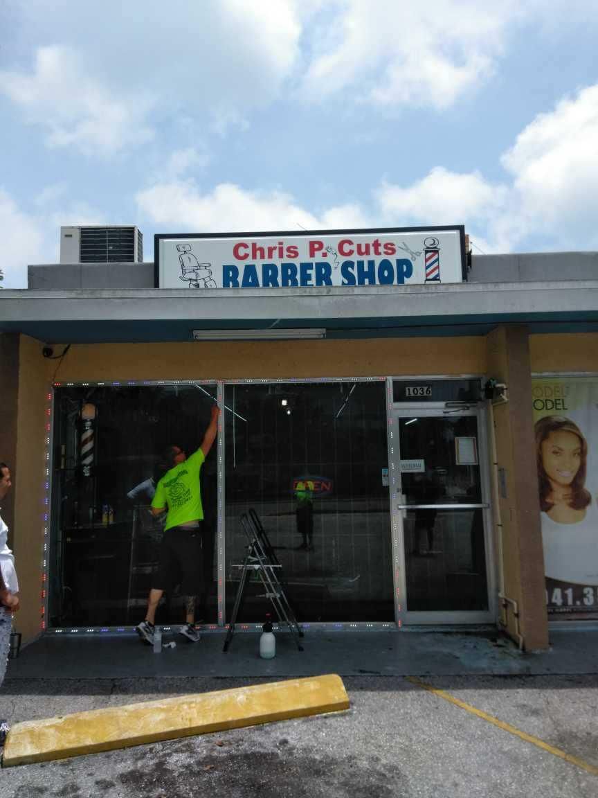 Chris P. Cuts barber shop storefront with a worker inside and a sign above the entrance