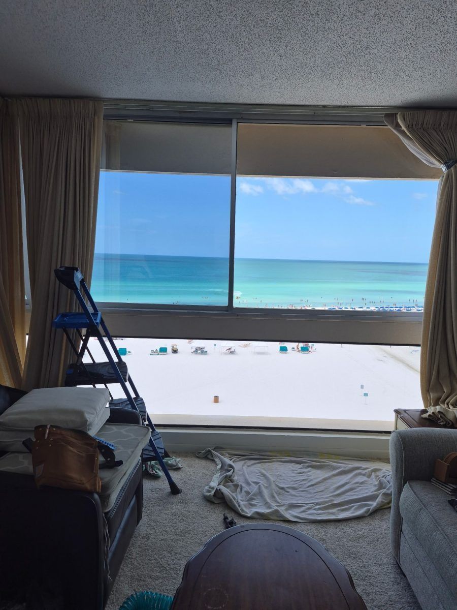 Beachfront room with open window, ladder, and towels facing a turquoise ocean view