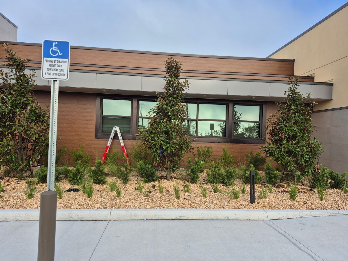 Accessible parking sign in front of a low brick building with shrubs and windows