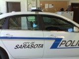Marked Sarasota police car side view with city logo and blue stripe