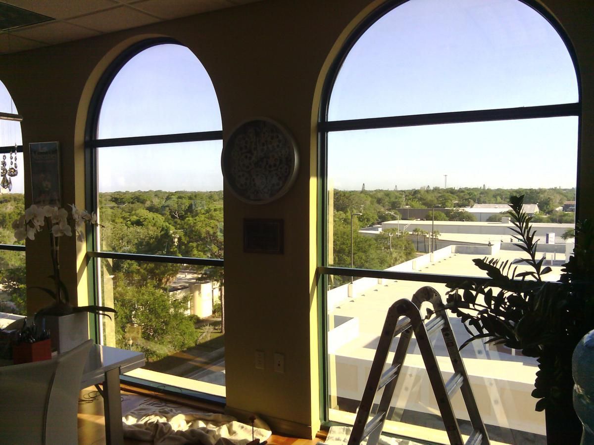 Indoor view through arched windows of a sunny cityscape with trees and rooftops
