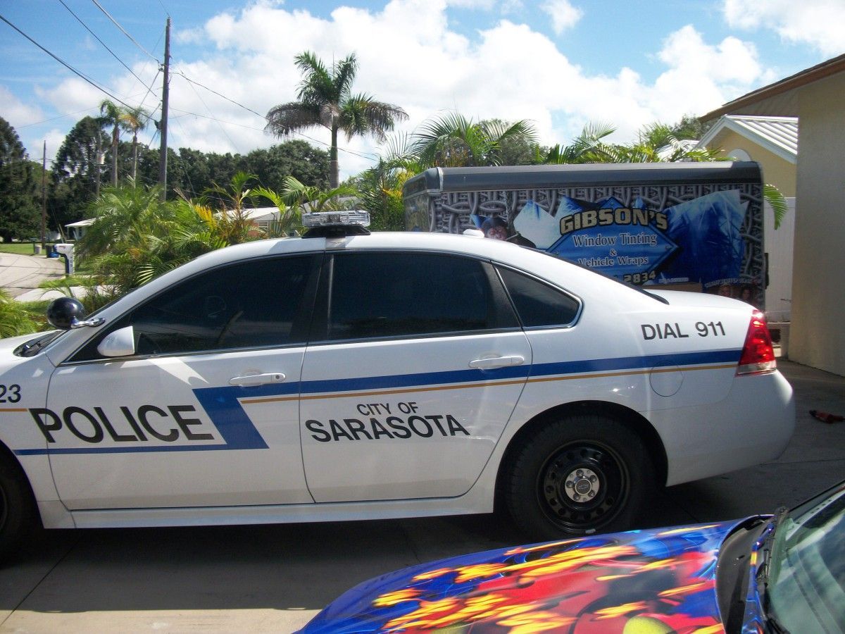 Sarasota police car parked beside a colorful mural on a sunny street