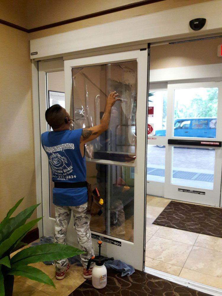 Worker cleaning glass entrance doors inside a building