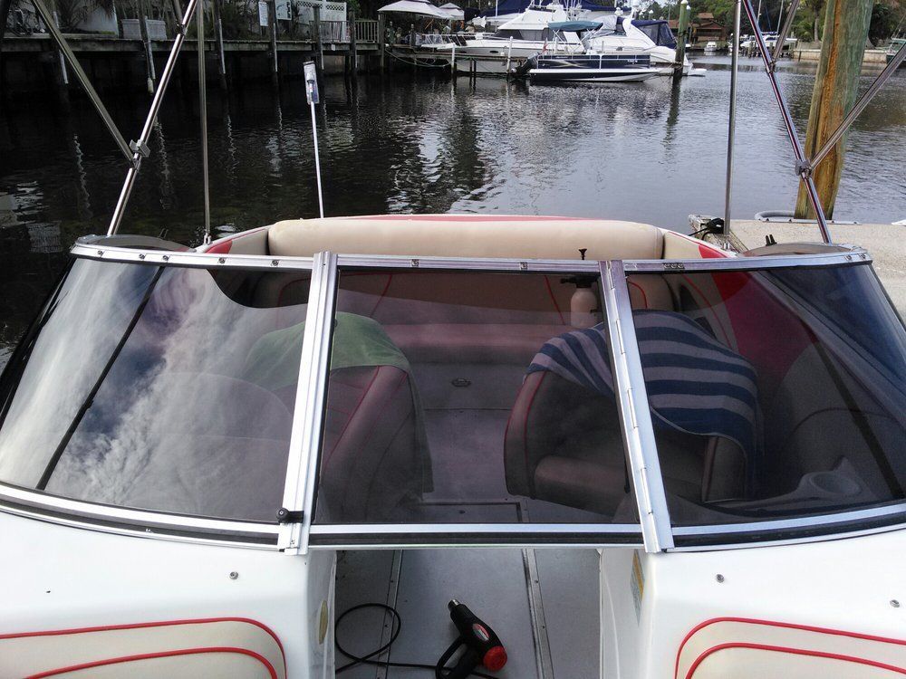Cockpit of a white boat with a tan canopy docked in a marina with other boats in the background