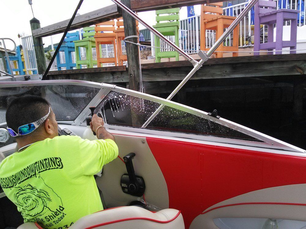 Person steering a small red boat beside a dock under a bridge, with colorful railings above.