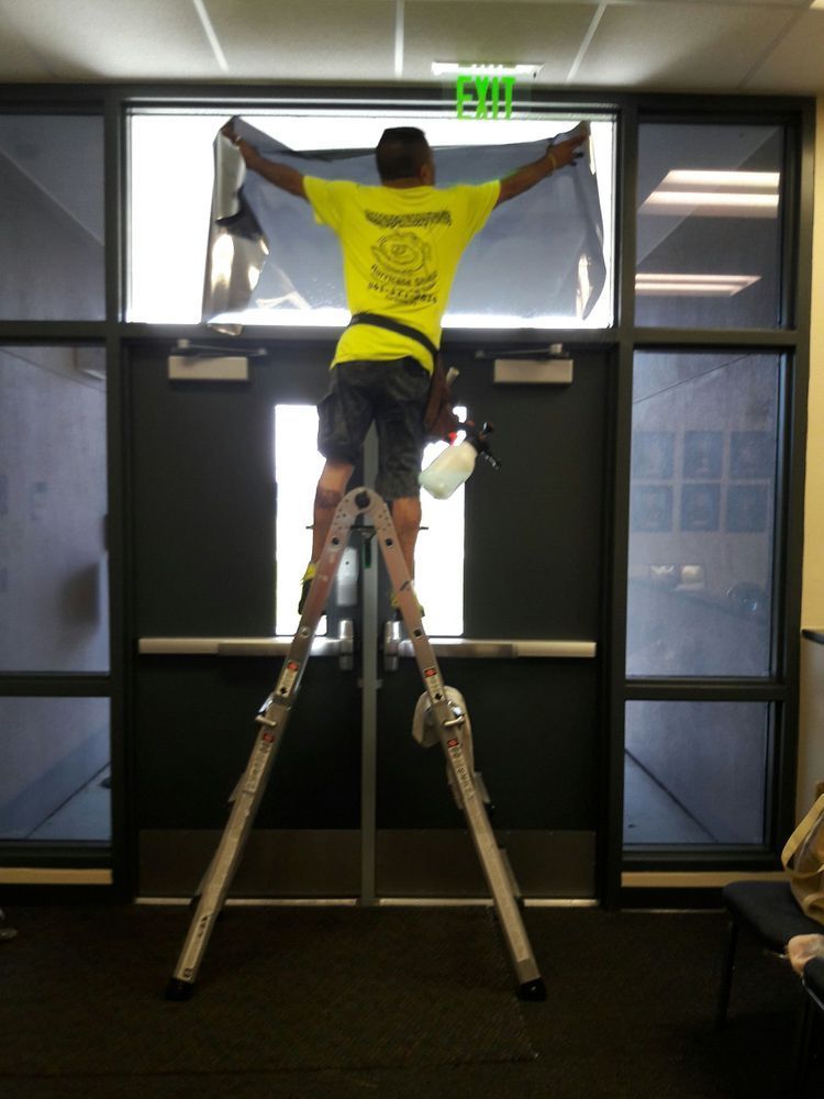 Person on a ladder painting or installing above a doorway in an indoor room