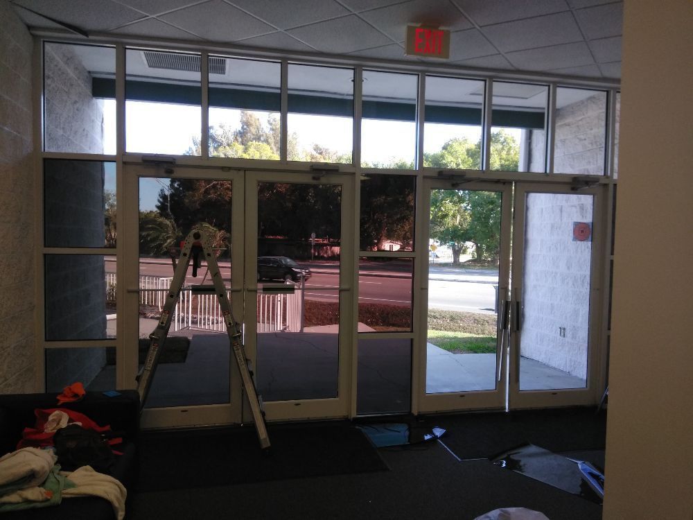Ladder inside a lobby with glass doors, looking out to trees and a street.