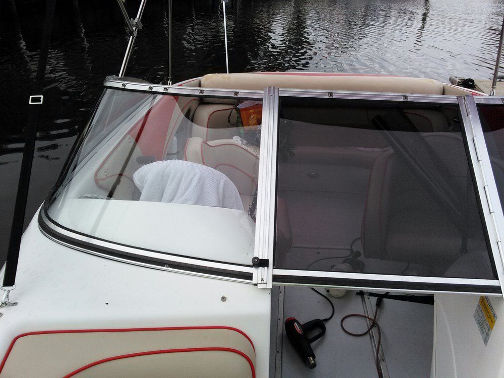 White boat deck with tinted windshield and reflections on calm water