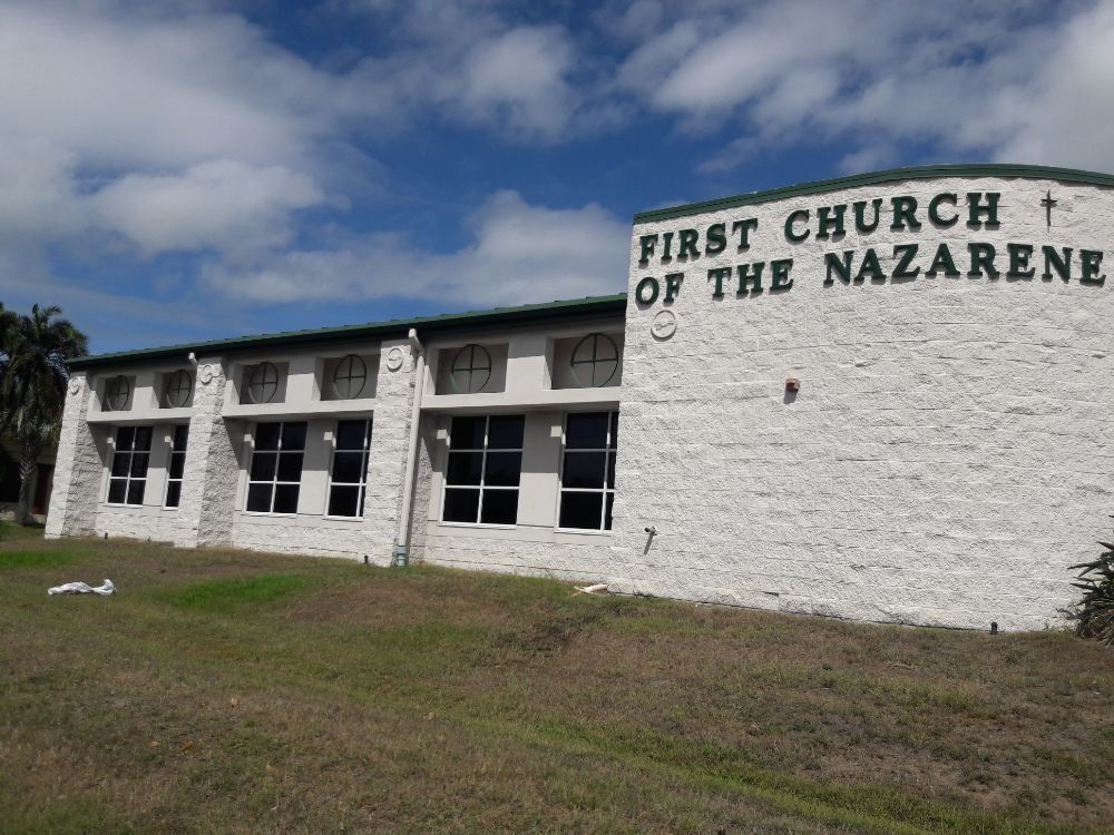 White church building with sign reading “First Church of the Nazarene” under a cloudy sky