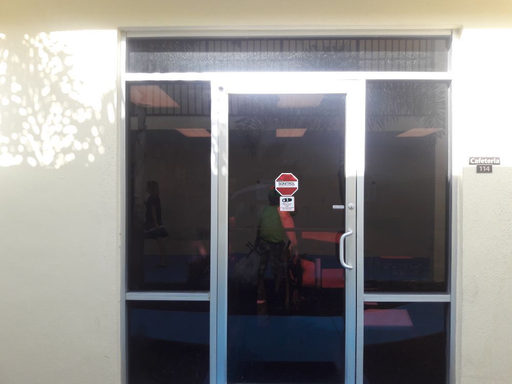 Glass double doors with a red sign on the center panel, viewed from outside a building.