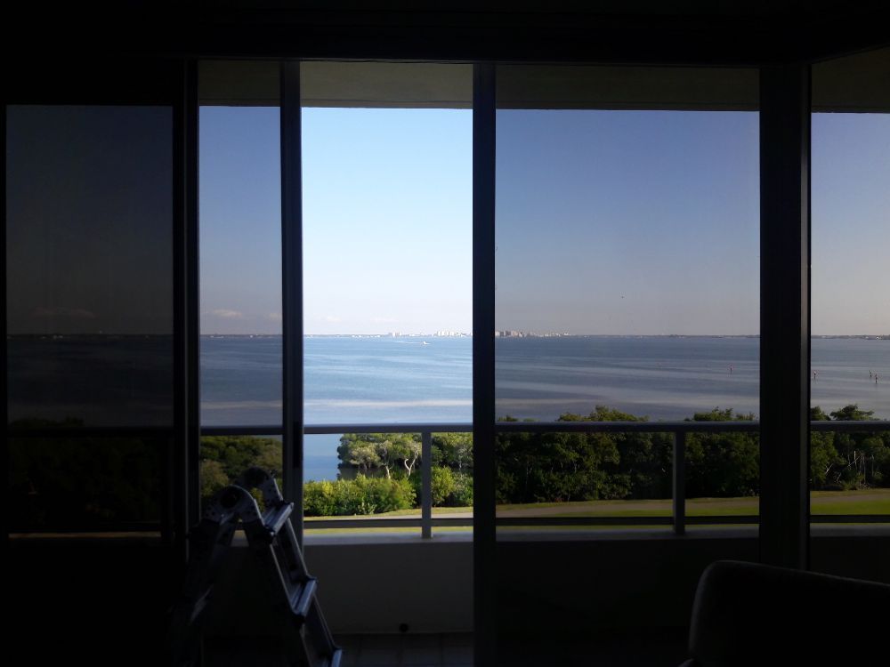 View through large windows of a calm ocean and distant shoreline at sunset
