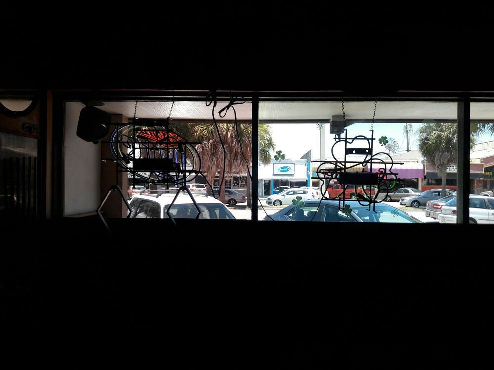 Interior view of a shop looking out at parked cars and a street through large front windows