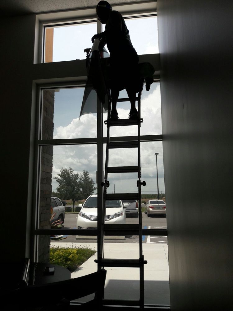 Silhouette of a person climbing a ladder inside a bright doorway, with cars visible outside.