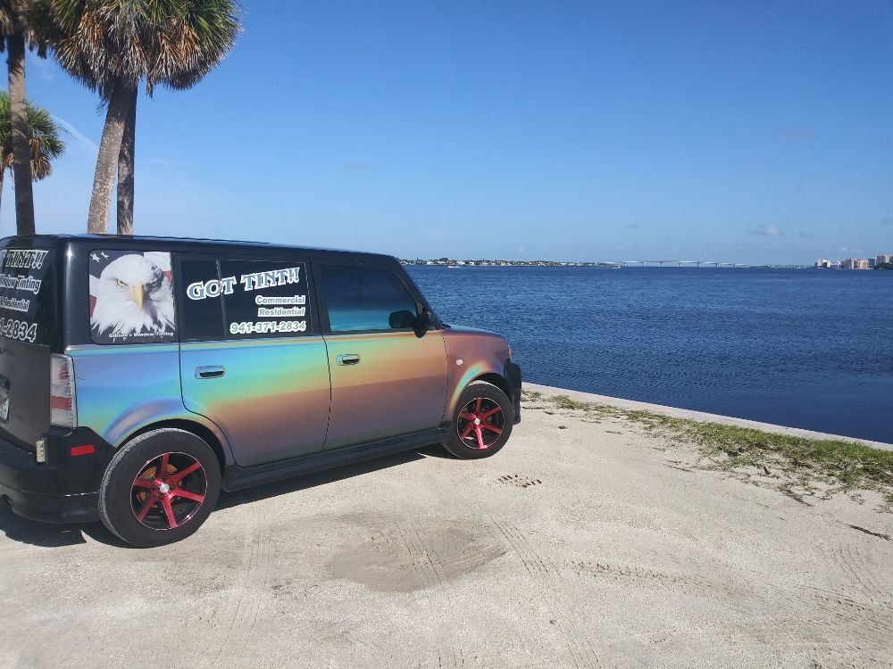 Color-shifting van parked by the waterfront with palm trees and blue sky