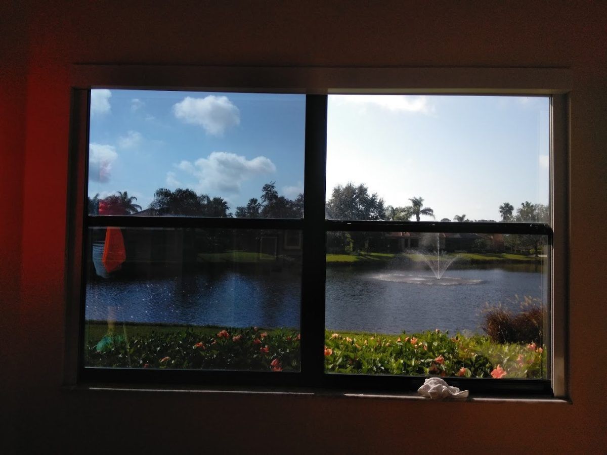 View through a window of a lake, trees, and blue sky with clouds