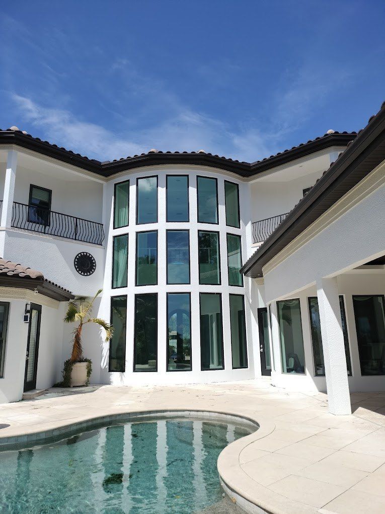 Modern white villa with curved glass windows and a turquoise pool under a blue sky