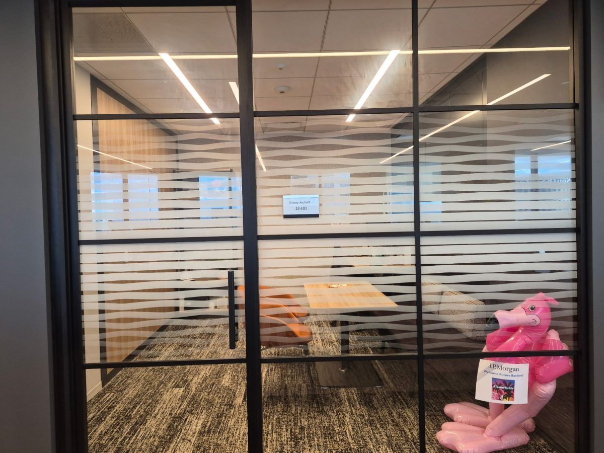 Office conference room seen through glass walls, with a table, chairs, and a pink stuffed toy on the right.