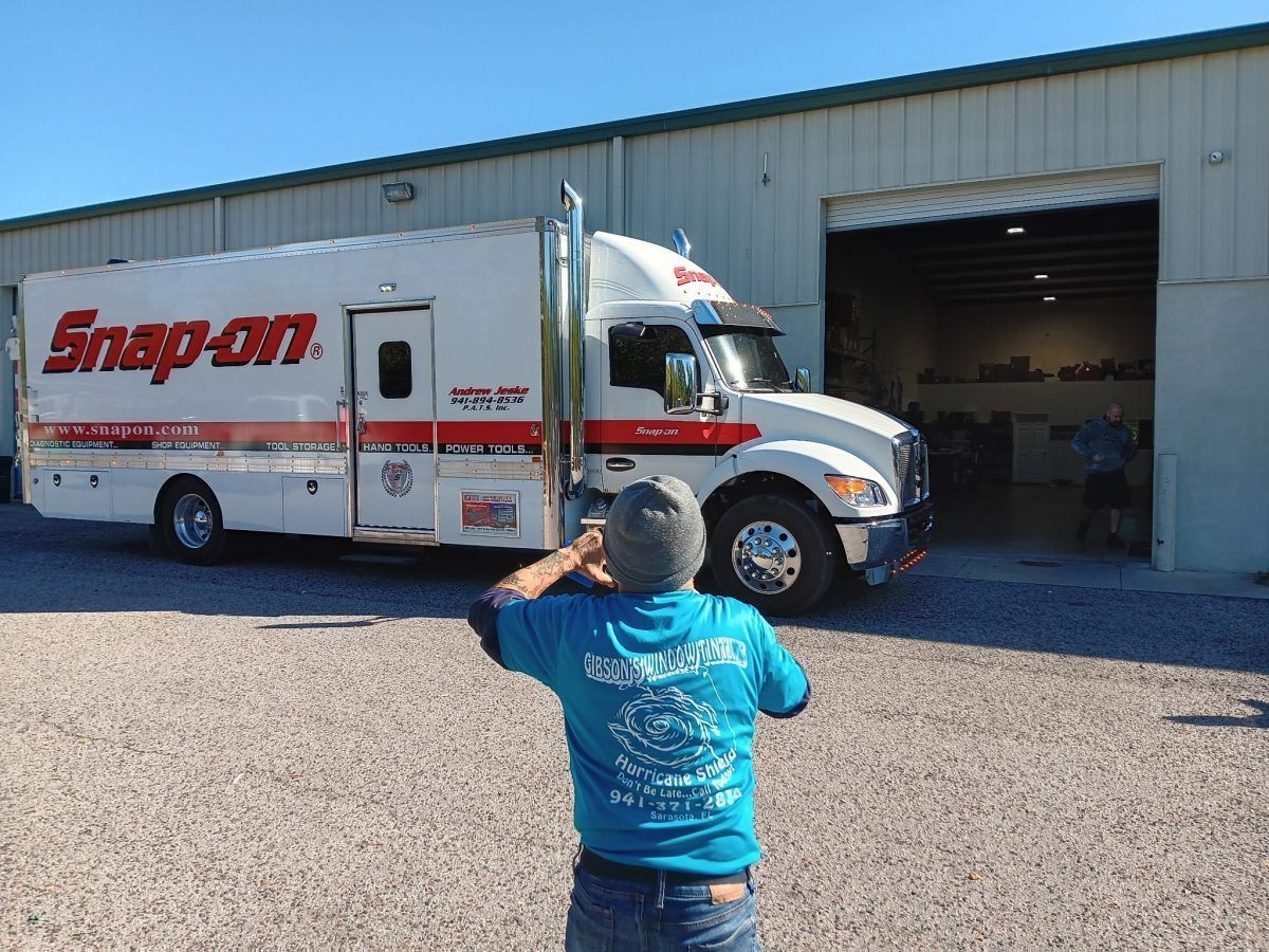 Snap-on truck parked outside a garage, with a person in a blue shirt photographing it.
