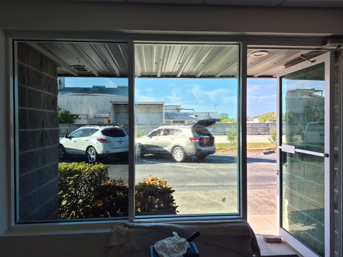 View through a window to a parking lot with cars and bright daylight outside