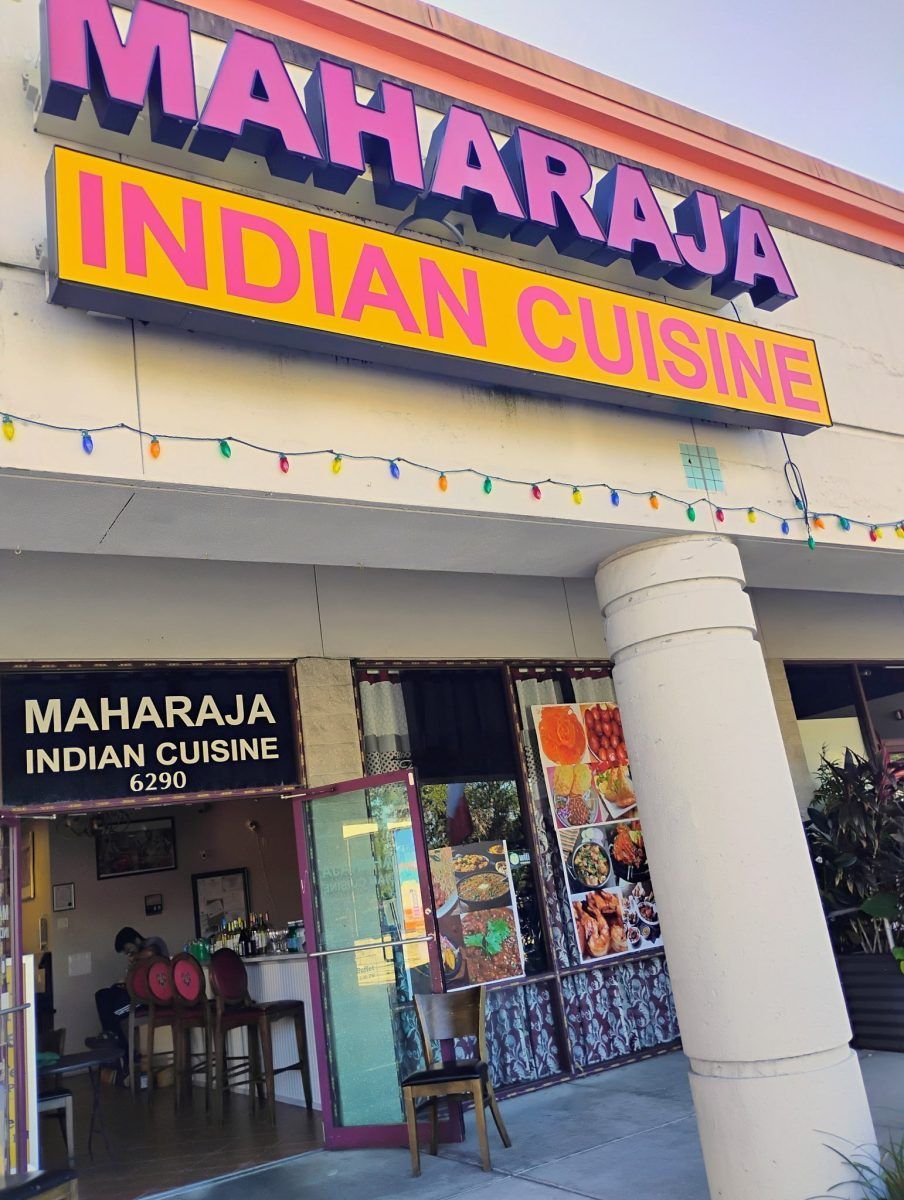 Maharaja Indian Cuisine storefront with bright pink and yellow sign above an open entrance.