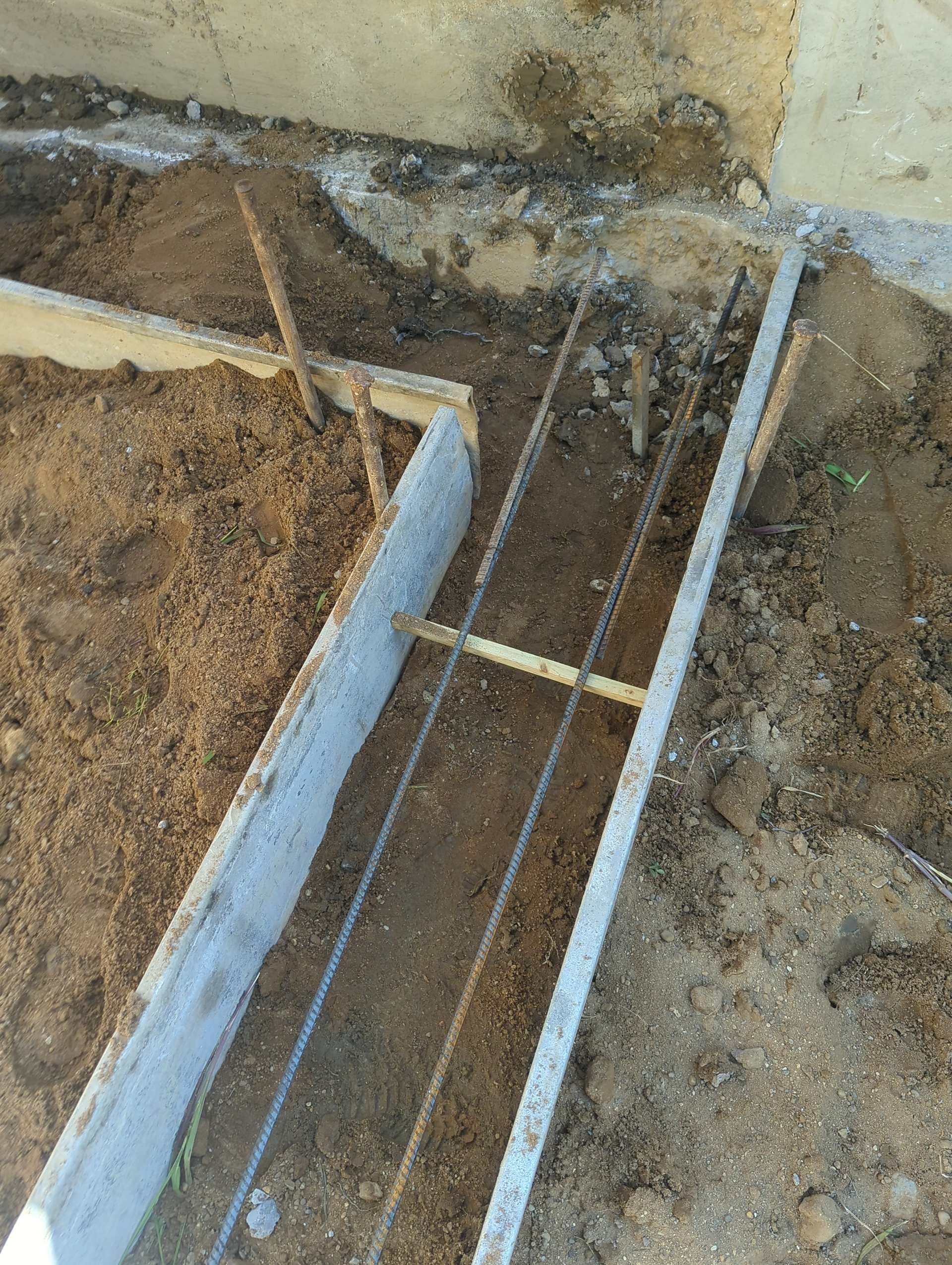 Wooden formwork and steel rebar prepared in a trench for a concrete foundation.