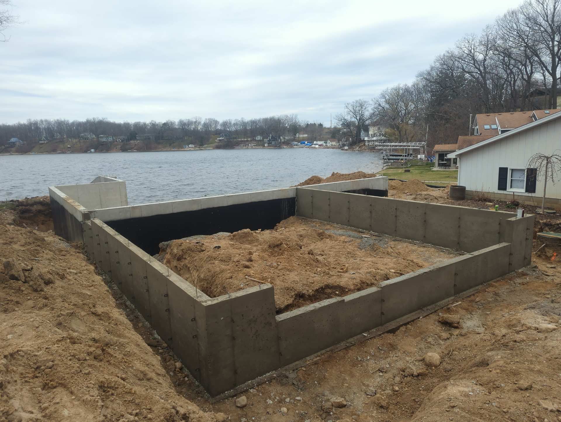 A concrete foundation for a house under construction on a lakeshore lot.