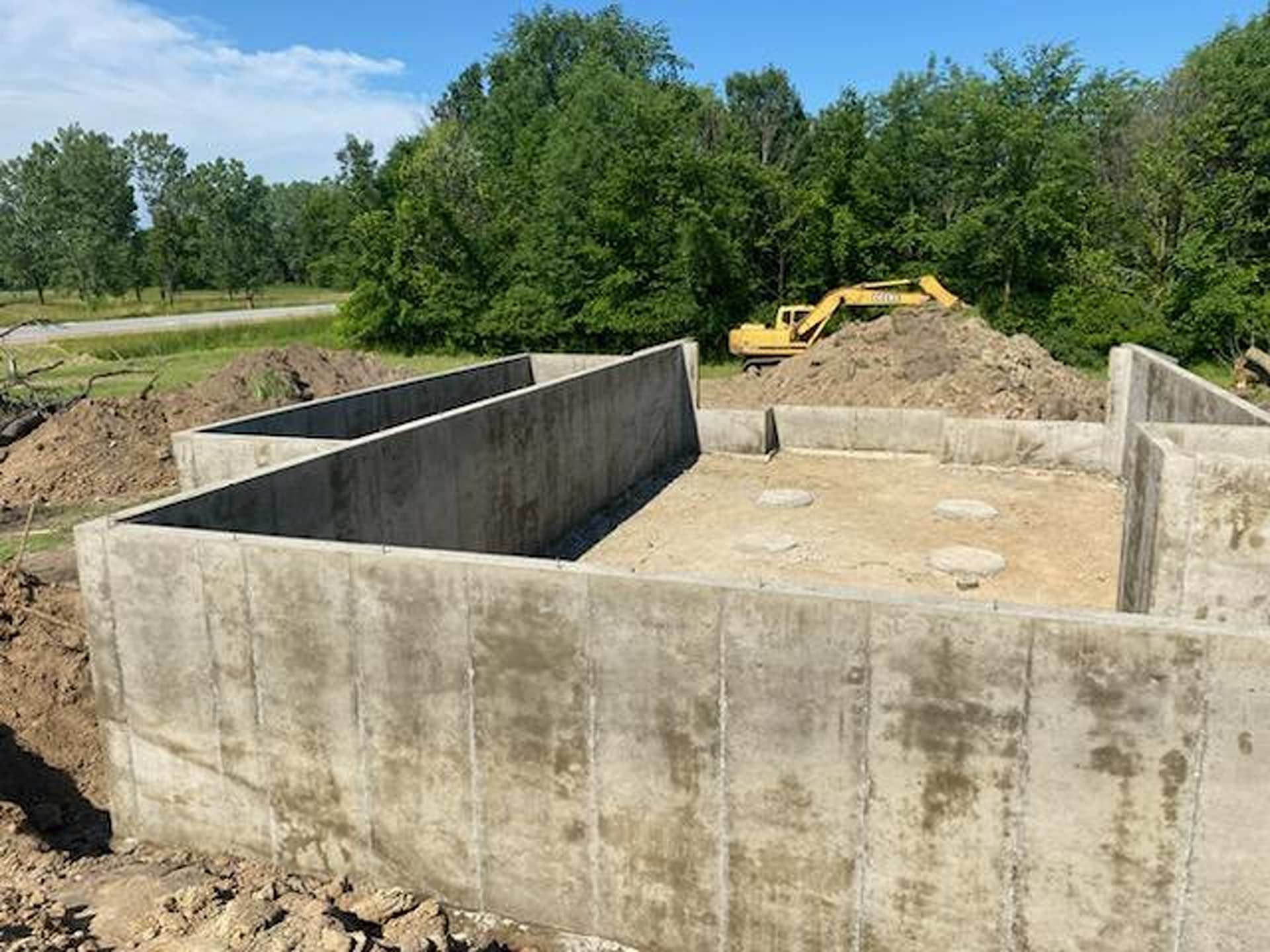 Concrete foundation walls for a new building under construction, with a construction vehicle in the background.
