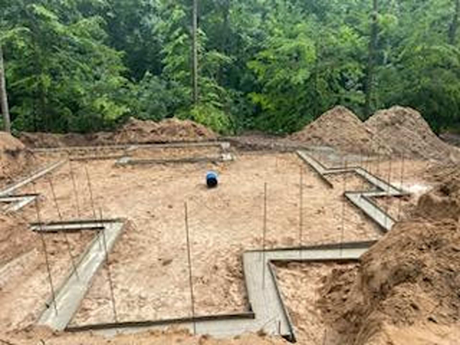 A concrete foundation for a new house under construction in a wooded area.
