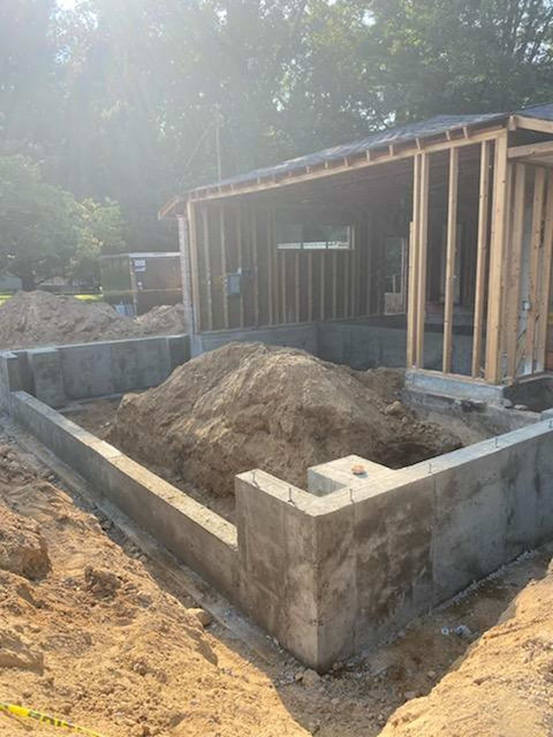 A construction site featuring a concrete foundation and wood framing for a new building addition.