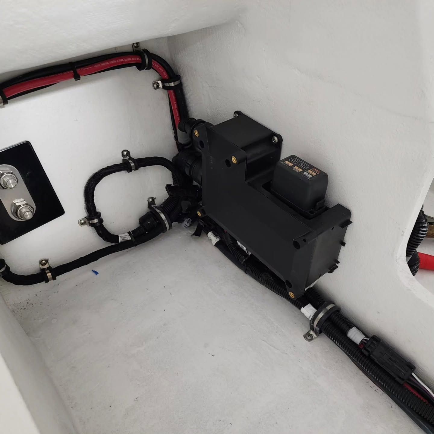 Black electronics box with red and black wiring mounted inside a white compartment.