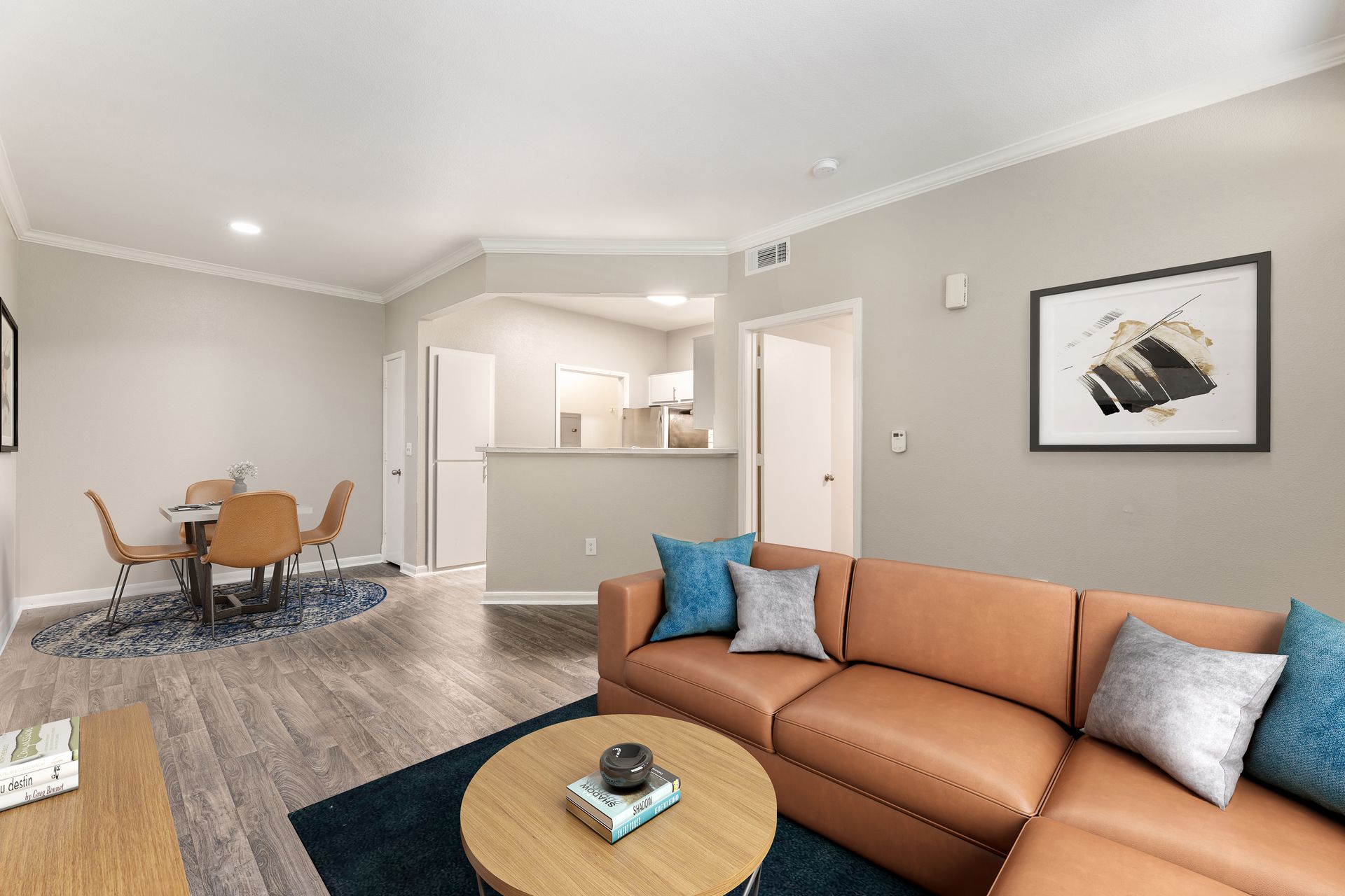 Empty living room with beige carpet, ceiling fan, and small kitchen pass-through.