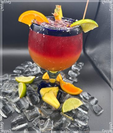 Colorful cocktail in a margarita glass, rimmed with blue. Garnished with citrus and pineapple, served over ice.
