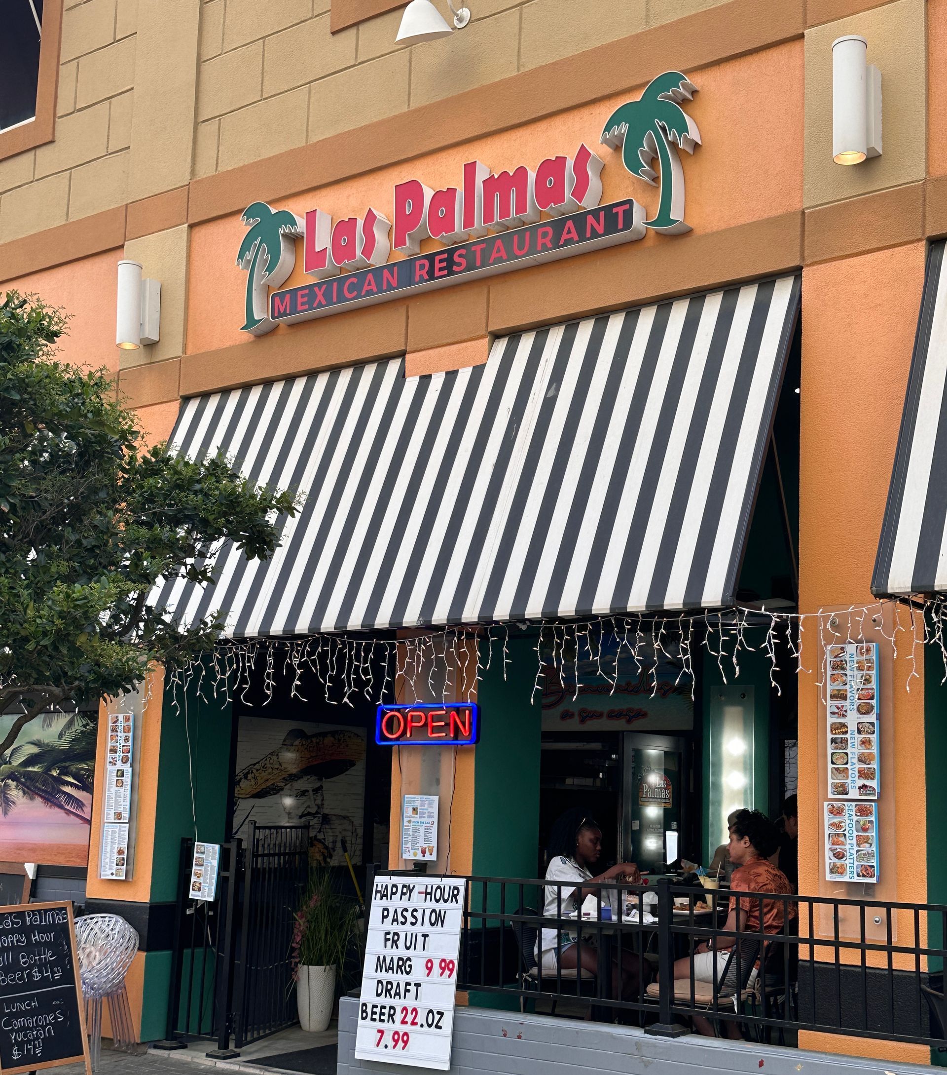 Exterior of Lai Palmetto Restaurant with striped awning. Open sign is visible.