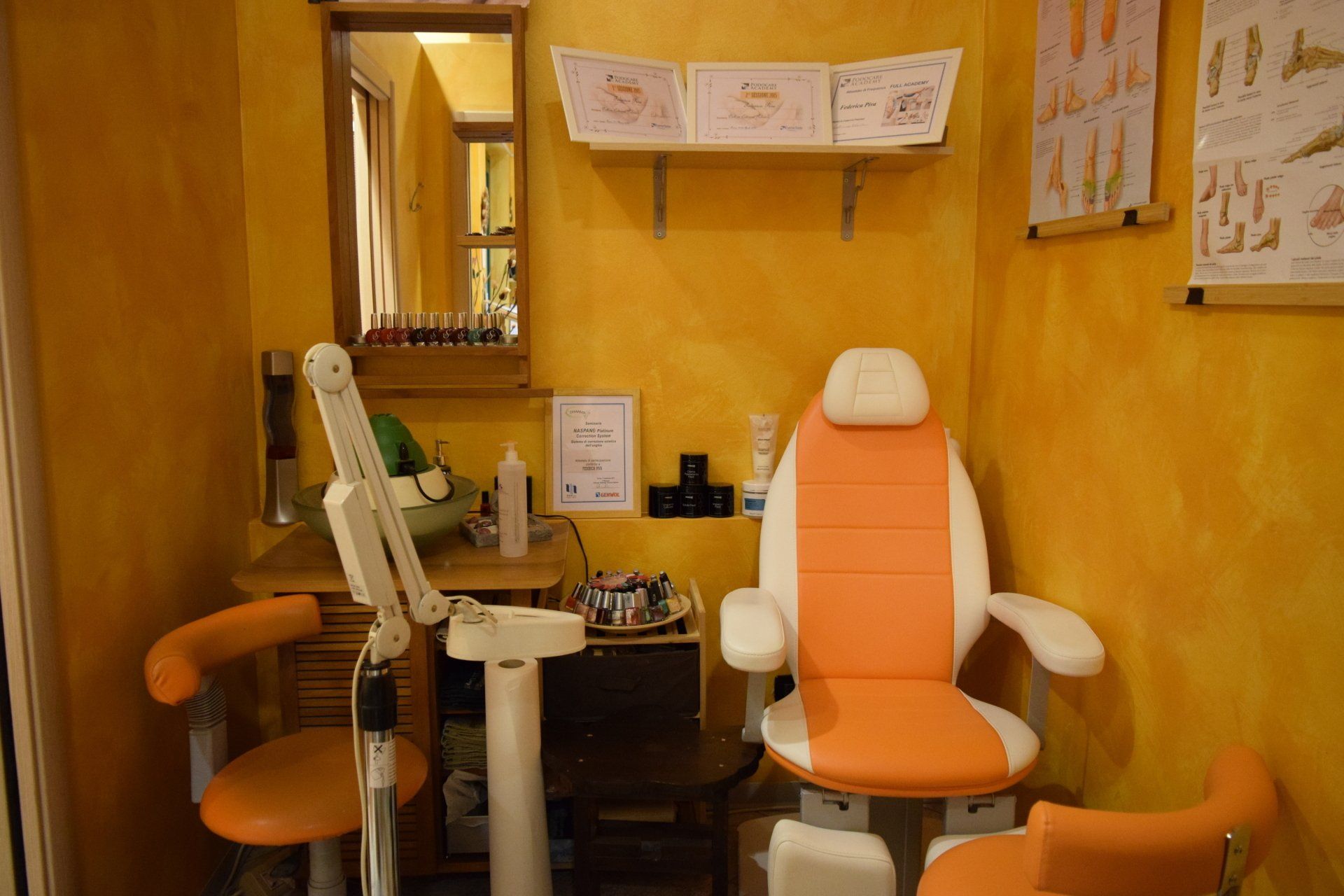 Sala per trattamenti a tema arancione: sedia, scrivania con attrezzatura, specchio, scaffali con diagrammi su pareti gialle.