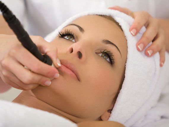 Donna sottoposta a un trattamento viso, con un professionista che le applica sul viso un dispositivo portatile.