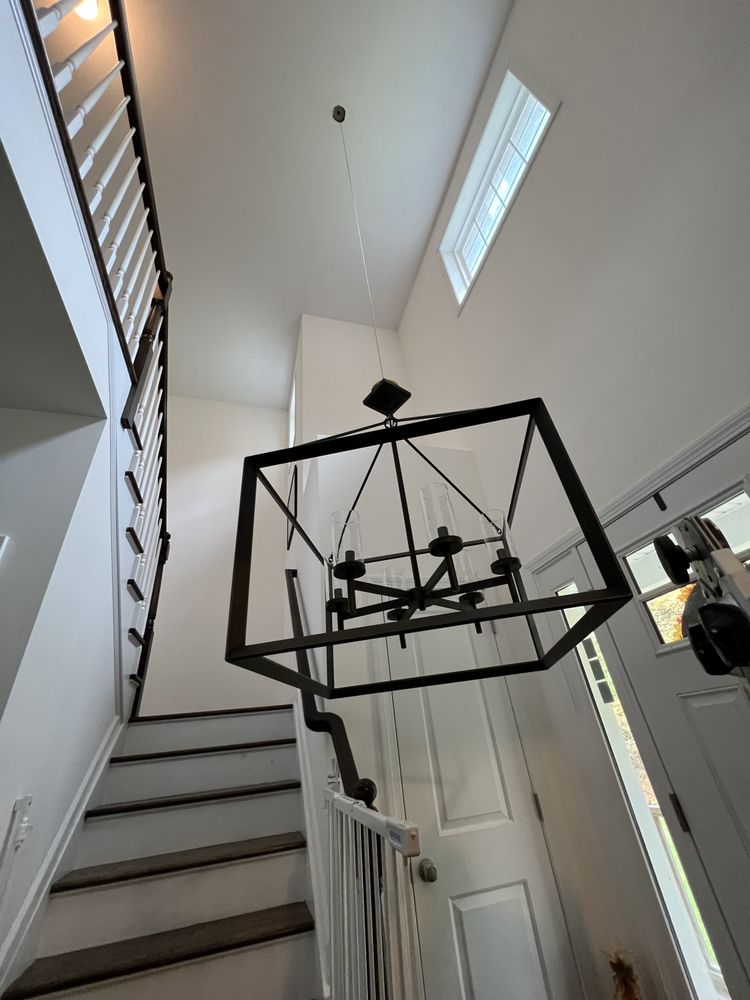Entryway with staircase, lantern chandelier, and white walls.