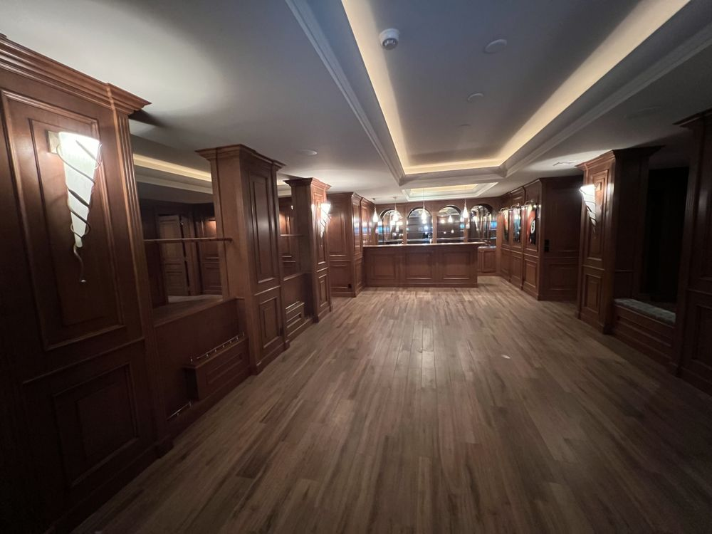 Empty room with wood paneling, wood floor, and recessed lighting.