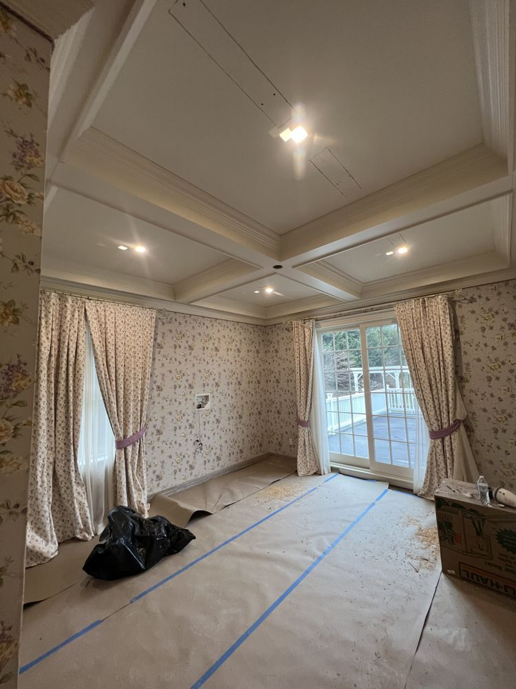 Room interior with floral wallpaper, curtains, a coffered ceiling, and a sliding glass door.