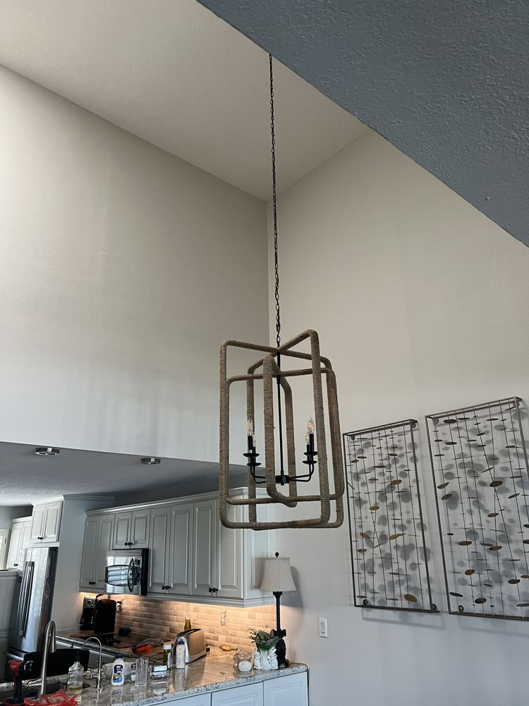 Wooden geometric pendant light fixture hanging in a kitchen with high ceilings.