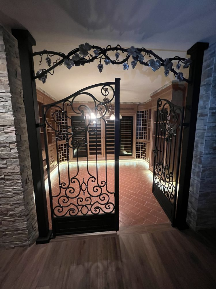Ornate wrought-iron gates open into a wine cellar. Vines and lights decorate the entryway.