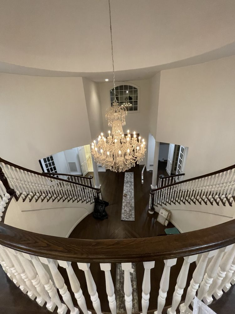 Grand foyer with a chandelier, curved staircase, and dark wood flooring.