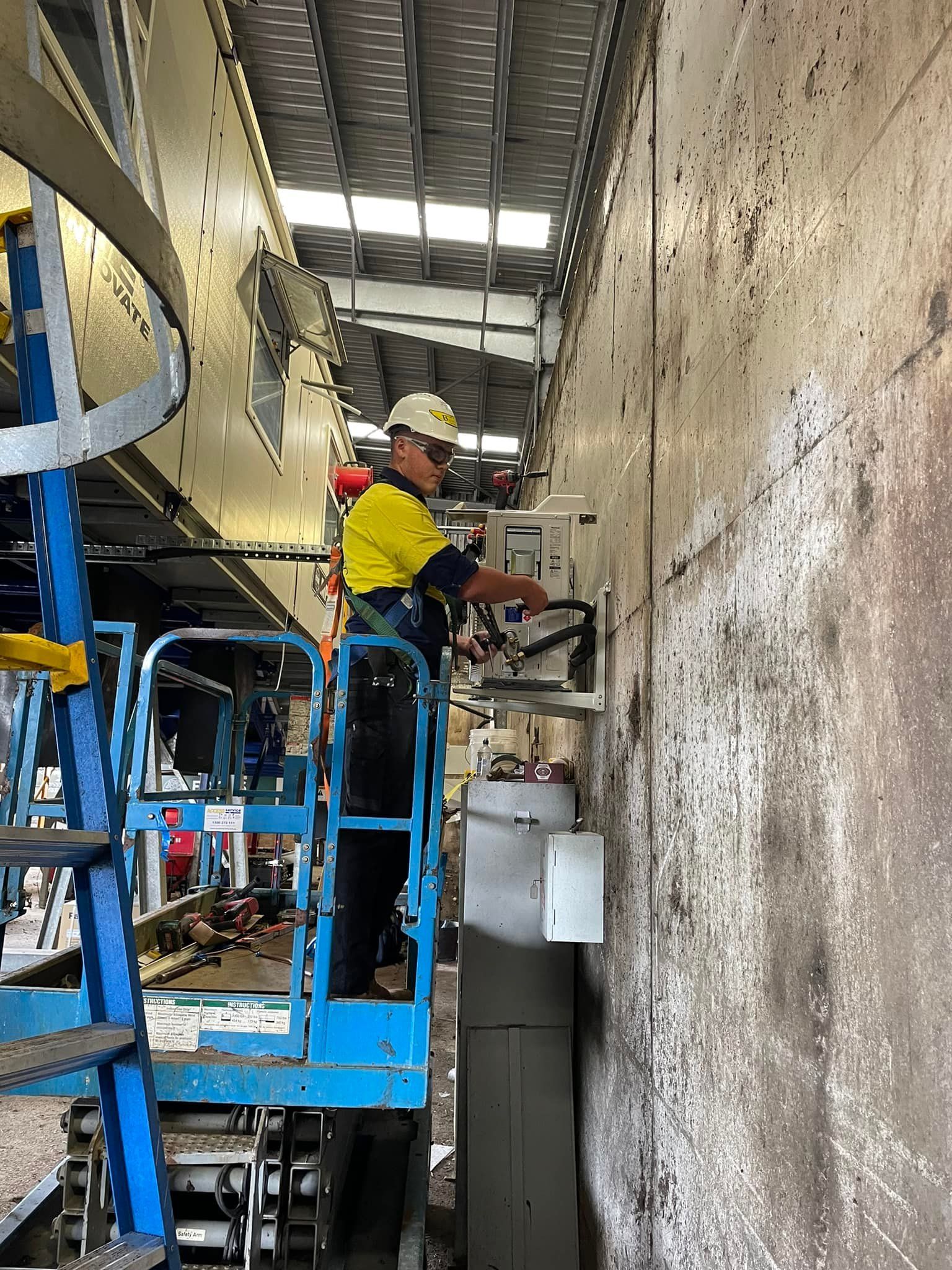 A Worker in Safety Gear on A Lift Working on Electrical — Leader Air Conditioning in Queanbeyan, NSW