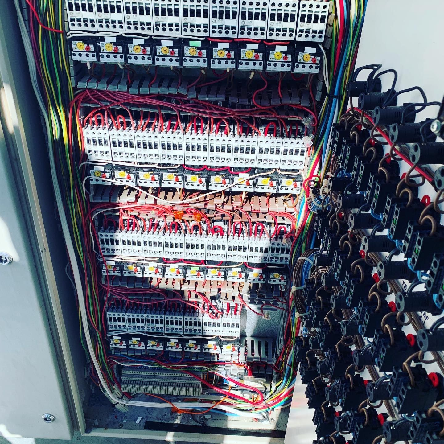Interior of an electrical panel filled with wiring, terminal blocks, and components; multi-coloured wires. — Leader Air Conditioning in Queanbeyan, NSW