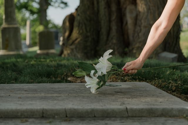 Hand offering white lily flowers at memorial service symbolizing sympathy and remembrance